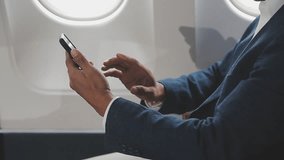 successful asian businessman in suit and glasses sits in private jet and uses smartphone, korean entrepreneur flies in an airplane and types on the phone online - Powered by Shutterstock - Get 15% off with code: PIKWIZARD15