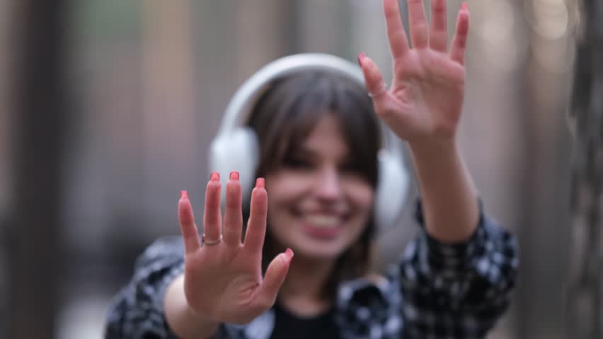 Young beautiful brunette listens to music on headphones outdoors. A woman dances joyfully to music among the maidens in the forest.