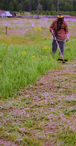 A man cleaning grass with a trimmer. Vertical 60 fps Vertical 4k footage.