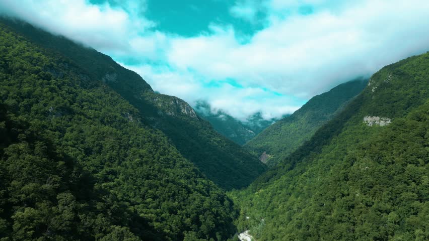 wonderful landscape flying over a green mixed deciduous forest in the mountains and rocks against a background of beautiful clouds
