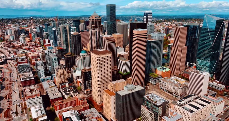 Flying closer to the beautiful modern high-rise buildings in the downtown of Seattle, Washington, US. Sunny cityscape of the metropolis from top.