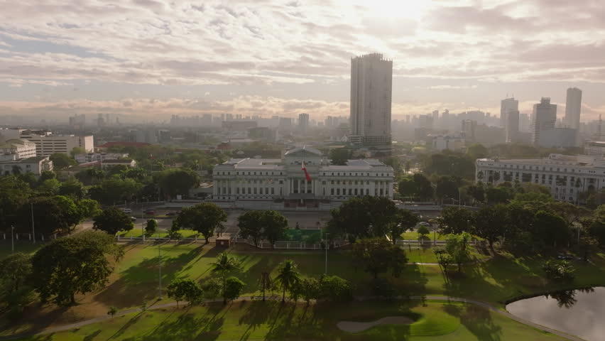 Aerial view of Manila National Museum of Fine Artscape at sunrise with high rise buildings, lush park, and serene shadows in a sunny day
