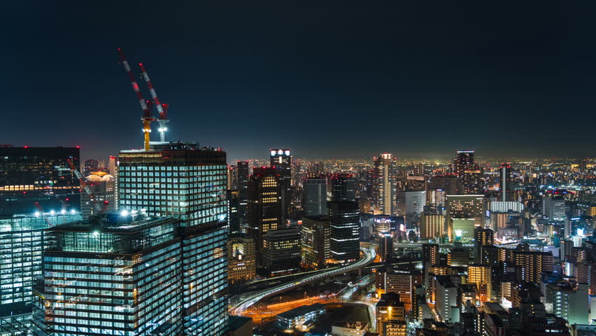 Timelapse view of Osaka skyline at night in Osaka, Kansai Region, Japan, zooming in. 
