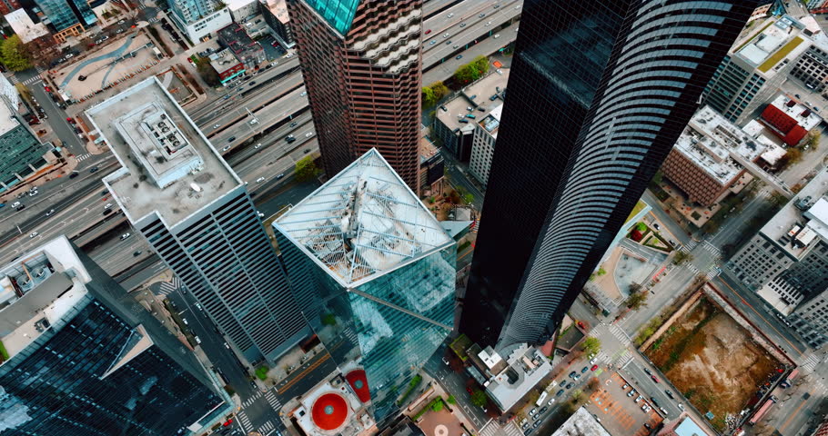 Spectacular highest skyscrapers in the downtown of Seattle, Washington, US. Drone rises over the tops of the towers. Wide-lane highway at backdrop with transport moving by.