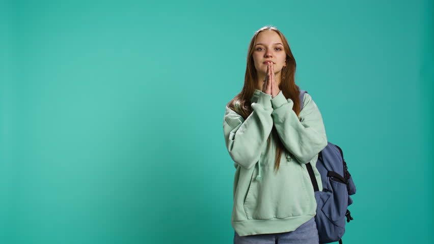 Hopeless young girl praying to deity for salvation. Religious teenager doing worship hand gesturing, asking for miracle, doing confession, isolated over studio background, camera B