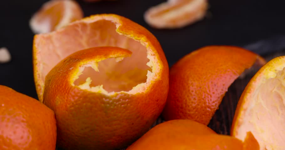 peeled , orange tangerines on the table in close-up, a large number of orange citrus fruits on a black slate surface