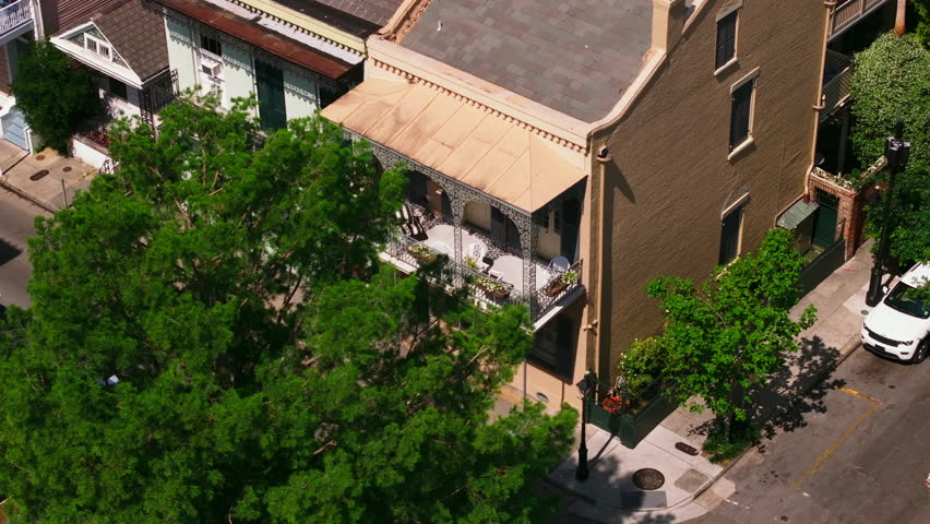 Aerial view of a picturesque street in New Orleans showcasing historic buildings with an iconic terrace, greenery, and classic architecture