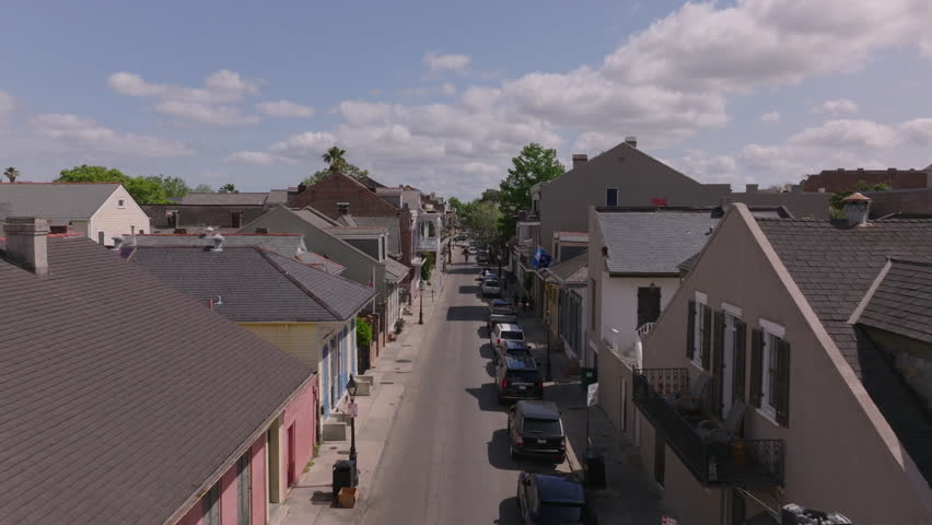 Lively streets of New Orleans with its traditional architecture, colorful houses of the French Quarter, and parked cars on a sunny day. Explore the charm of this historic louisiana neighborhood