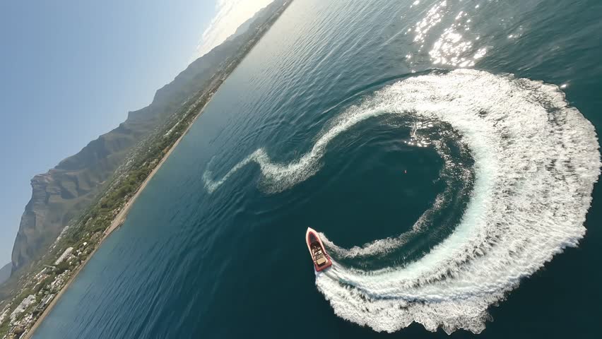 Aerial drone view fast red motor boat move blue water surface. Person sail rental speedboat open sea. Happy free man float speed motorboat leave circle wave trail. Freedom concept Active ocean tourism