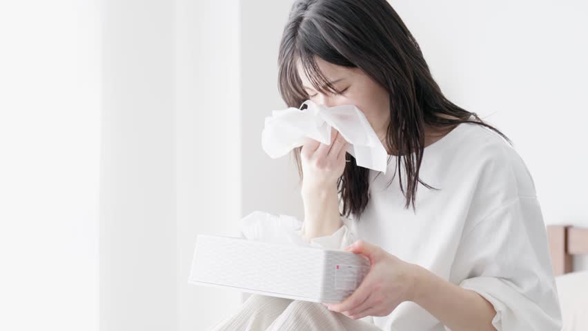 Woman blowing her nose in the room