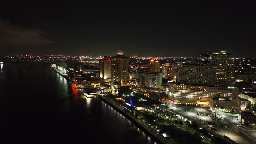Breathtaking aerial view of New Orleans at night, with city lights and the tranquil mississippi river with boats docking under modern architecture
