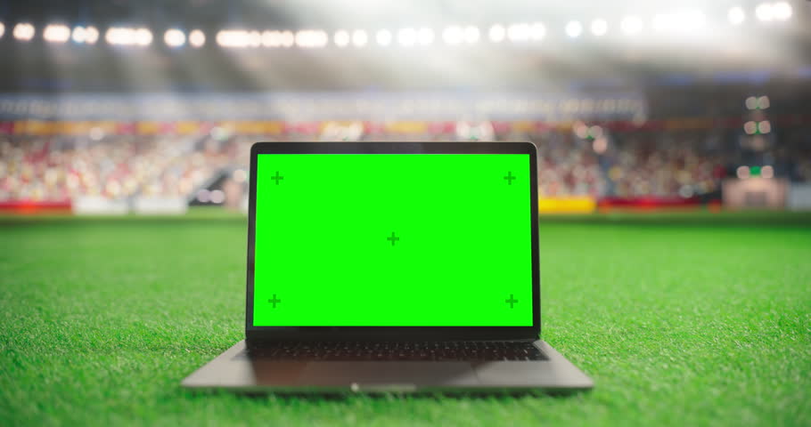 Laptop Computer with a Green Screen Mock Up Display with a Soccer Ball Rolling in the Background on a Stadium Field at Night. Template for Software, Streaming, Sports Betting, Multimedia Content