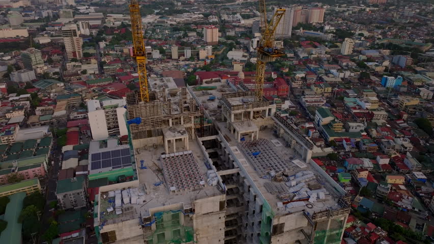 Aerial shot of a busy construction site in Manila, with tall cranes and buildings on the rooftop among urban structures