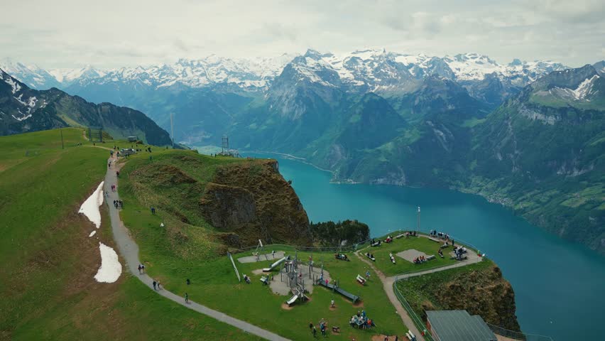 Fronalpstock in Stoos with snowy rocky Swiss Alps mountains on horizon. Aerial dorne view of lake Lucerne with snowy rocky mountain peaks. Picturesque nature landscape in Switzerland