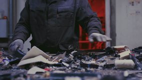 Man sorts metal rubbish. Male sorts garbage, electronics or plastic. Taking care of the environment. Waste recycling plant or garbage factory. Conveyor belt, trash moving along the line - Powered by Shutterstock - Get 15% off with code: PIKWIZARD15