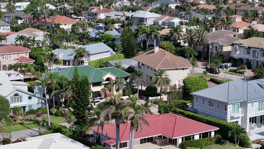 Aerial view surveys Boca Raton waterfront homes with private docks, palms, tiled roofs, streets, and Intracoastal water, 2024.