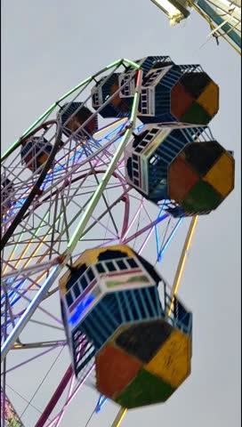 Closeup of multi-coloured Giant Wheel during Dussehra Mela in Delhi, India. Bottom view of Giant Wheel swing. Ferris wheel with colourful cabins during day time.