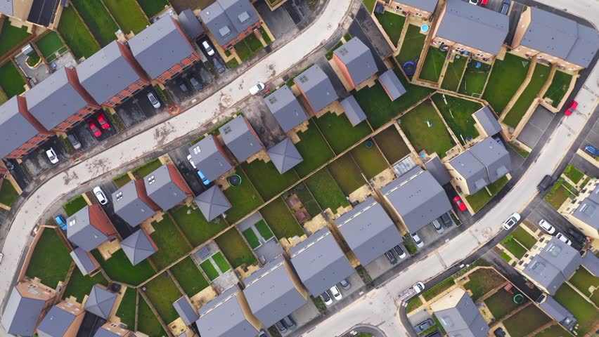 4K aerial footage directly above a new build housing estate with affordable homes for first time buyers with upward motion zooming out and camera rotation 