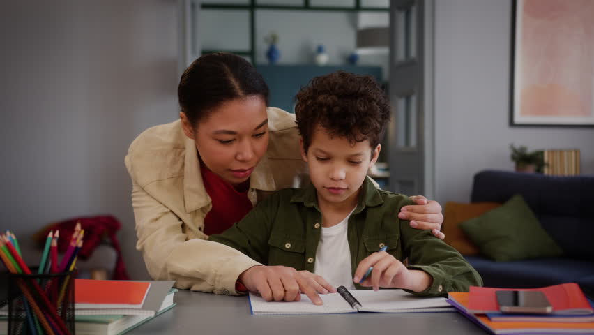 African American family little boy child kid son pupil studying home education writing homework task learning study mother woman female mom come in room walk go embrace cuddle schoolboy help with math - Powered by Shutterstock - Get 15% off with code: PIKWIZARD15