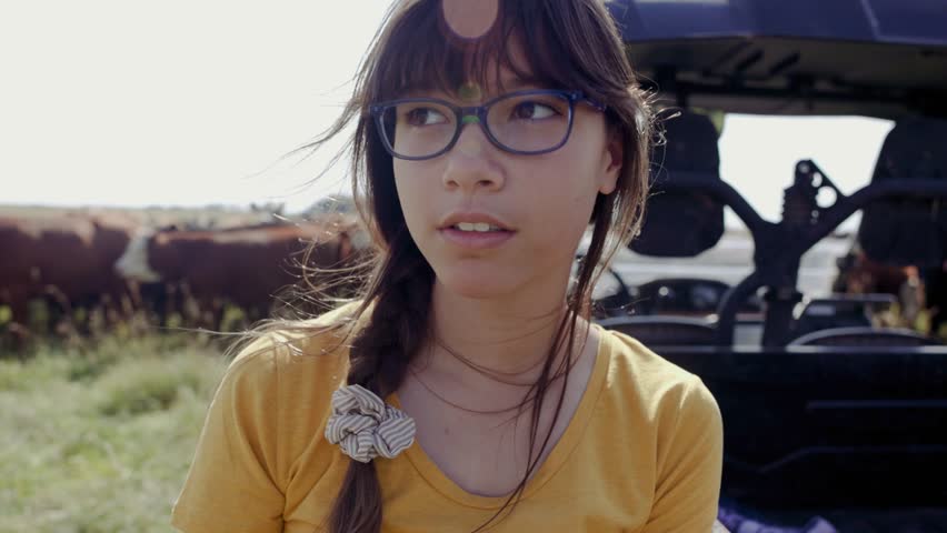 Close up smiling girl putting on cowboy hat on cattle ranch