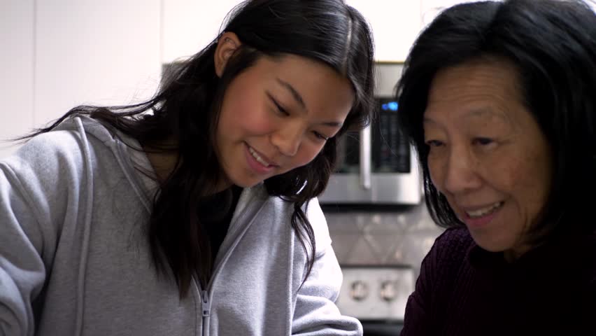 Happy grandmother and granddaughter baking cherry pie in kitchen