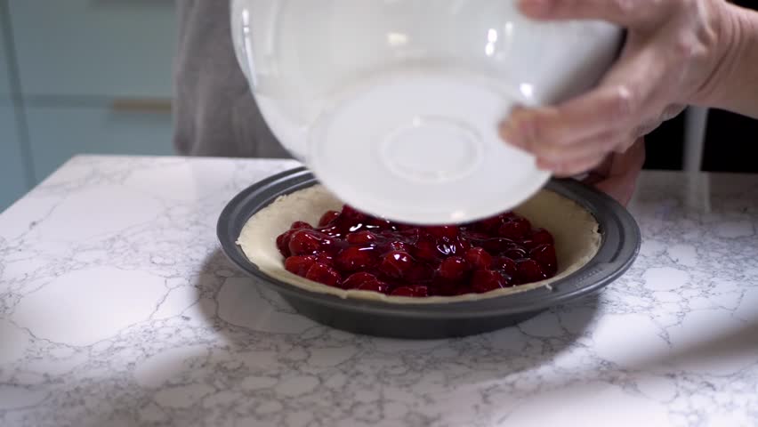 Grandmother and granddaughter baking cherry pie in kitchen