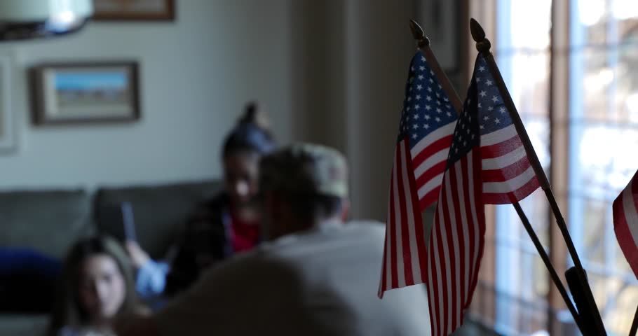 Army soldier father playing chess with daughters behind American flags