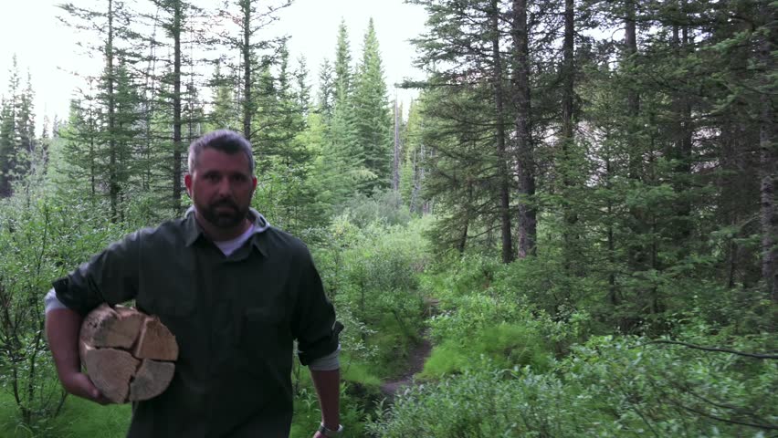 Man carrying firewood on trail in woods