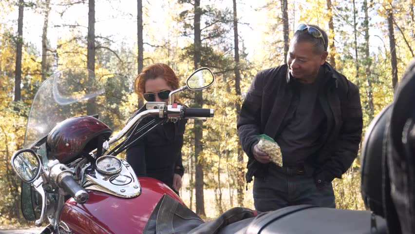 Slow motion of motorcyclists sharing snack in forest