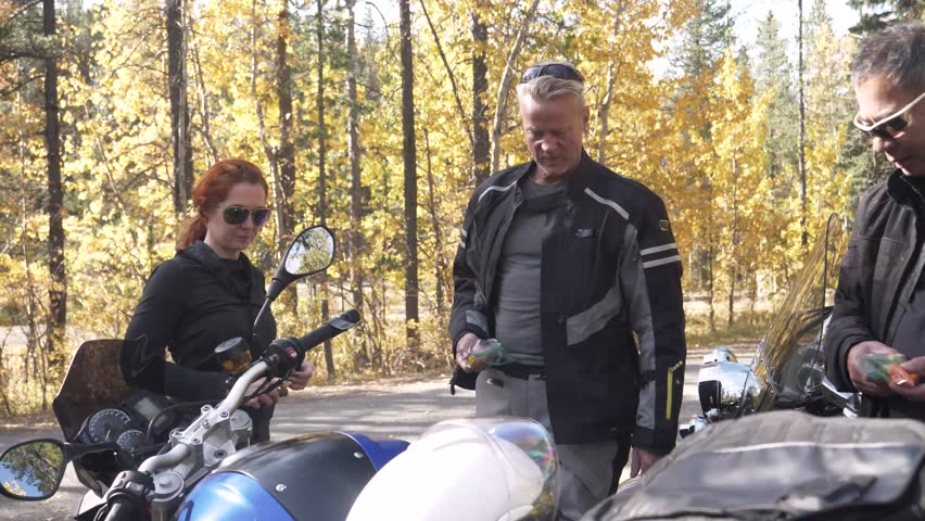 Motorcyclist chatting next to motorbe in forest