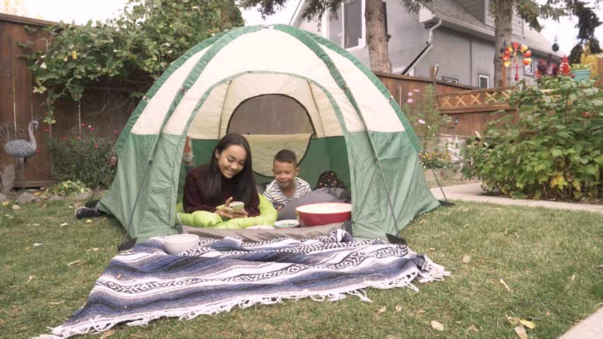Siblings using digital devices inside tent
