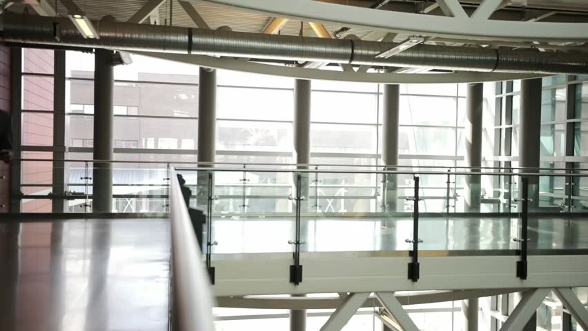 Businessman with smart phone walking on office balcony