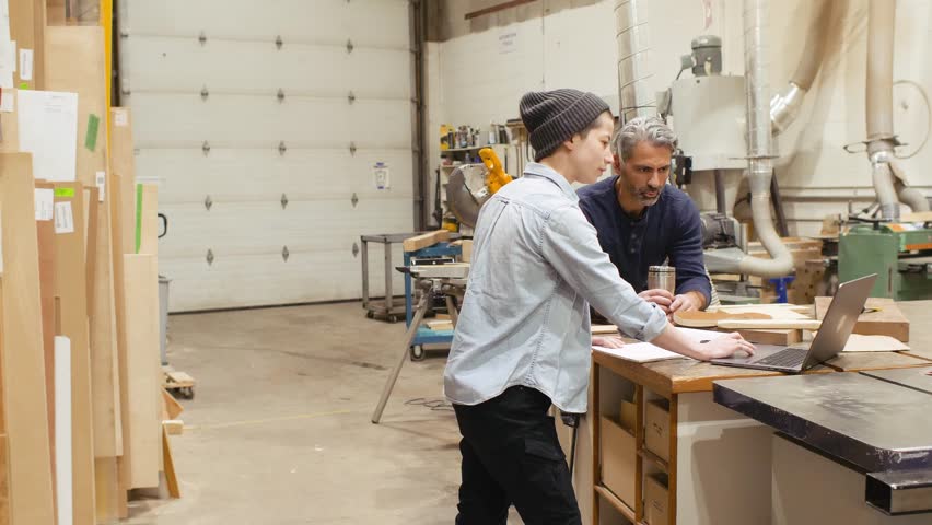 Carpenters talking using laptop in workshop