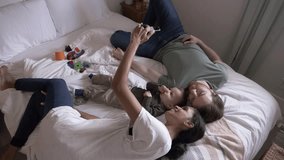 Affectionate couple and toddler son relaxing and taking selfie on bed - Powered by Shutterstock - Get 15% off with code: PIKWIZARD15
