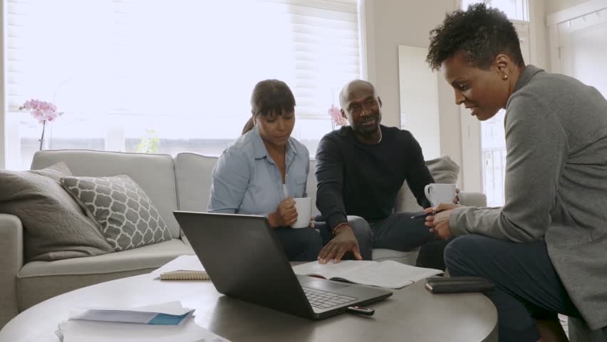 Financial advisor meeting with couple discussing paperwork in living room