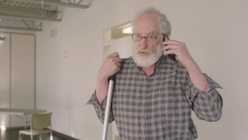Senior male volunteer talking on smart phone in community center
