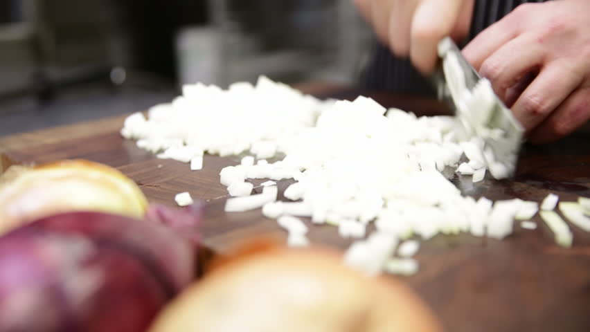 Chef chopping onion on cutting board