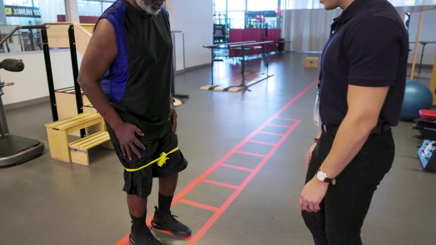 Physical therapist guiding patient doing lateral band walk in clinic