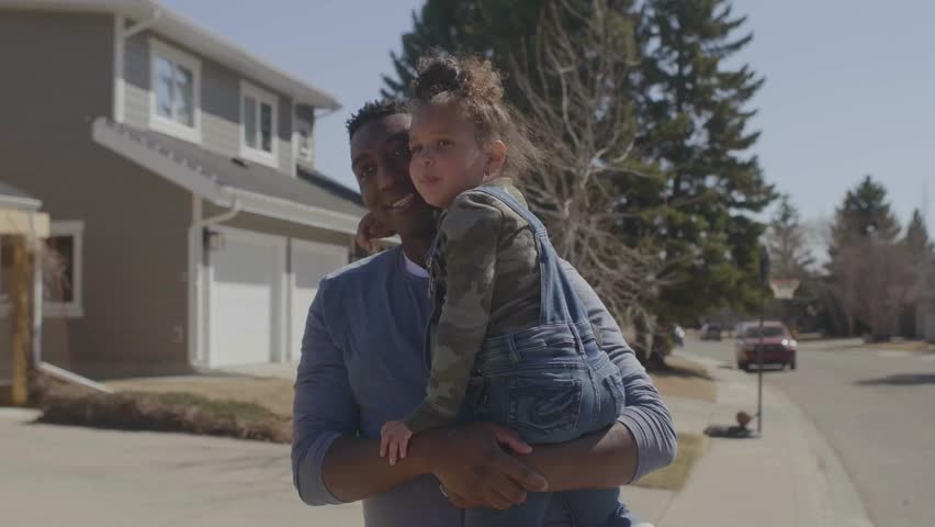 Father walking with daughter in arms in neighborhood