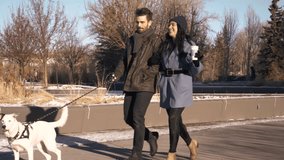 Young couple walking dog in sunny snowy winter park - Powered by Shutterstock - Get 15% off with code: PIKWIZARD15