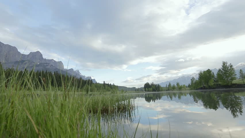 Clouds reflected in calm lake near mountains WS LR pan