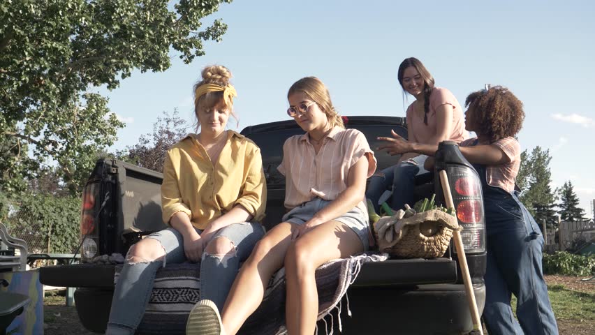 Slow motion of friends talking on rear of pickup truck