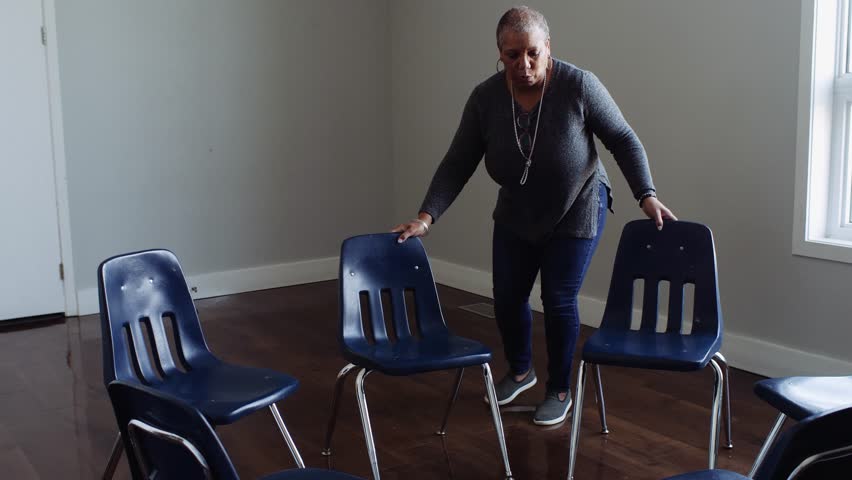 Female volunteer arranging chairs in circle in community center
