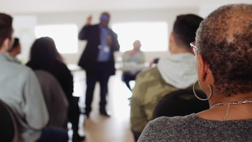 Audience listening to community leader talking at town hall meeting