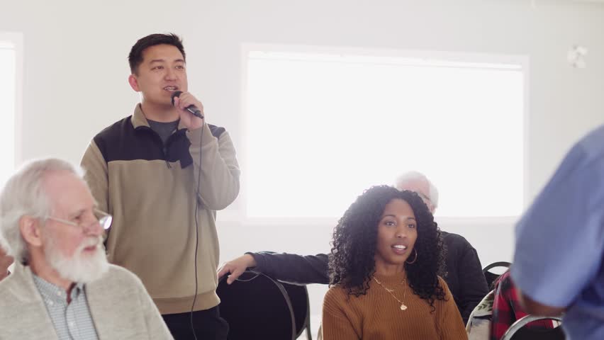 Man with microphone asking question in community town hall meeting