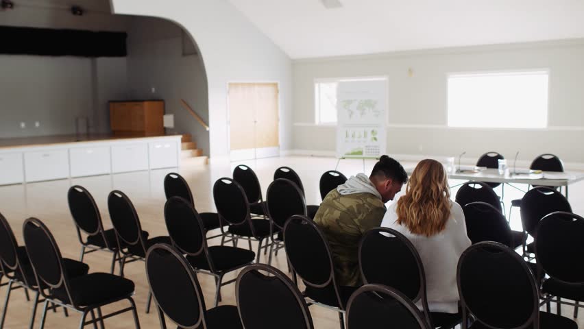 Young couple talking waiting in audience in community center