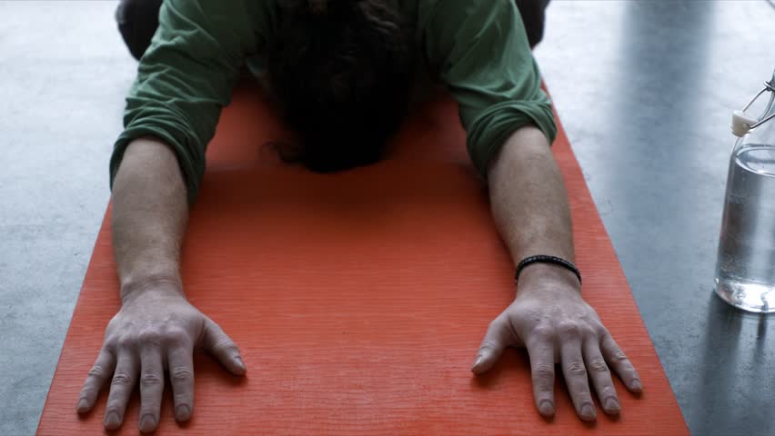 Man practicing yoga child pose on yoga mat
