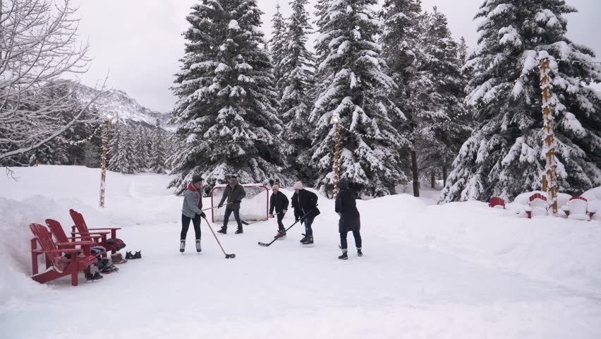 Family playing ice hockey at snowy winter resort