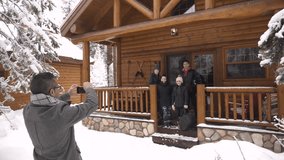 Father photographing family on snowy winter log cabin porch - Powered by Shutterstock - Get 15% off with code: PIKWIZARD15