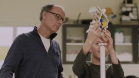 Junior high teacher helping student assembling wind turbine science project - Powered by Shutterstock - Get 15% off with code: PIKWIZARD15